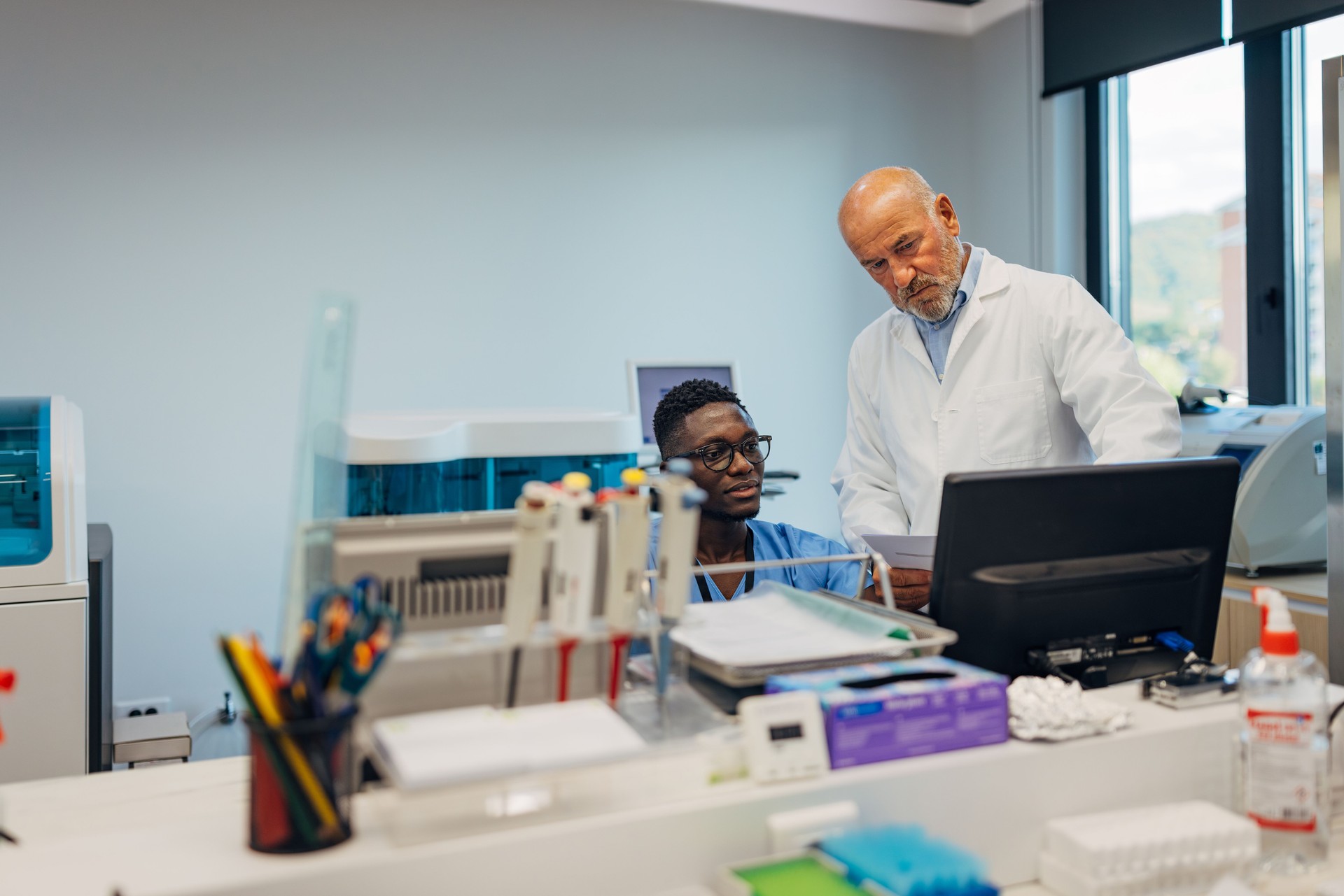 Two diverse scientists working attentively with a computer in a clinical laboratory